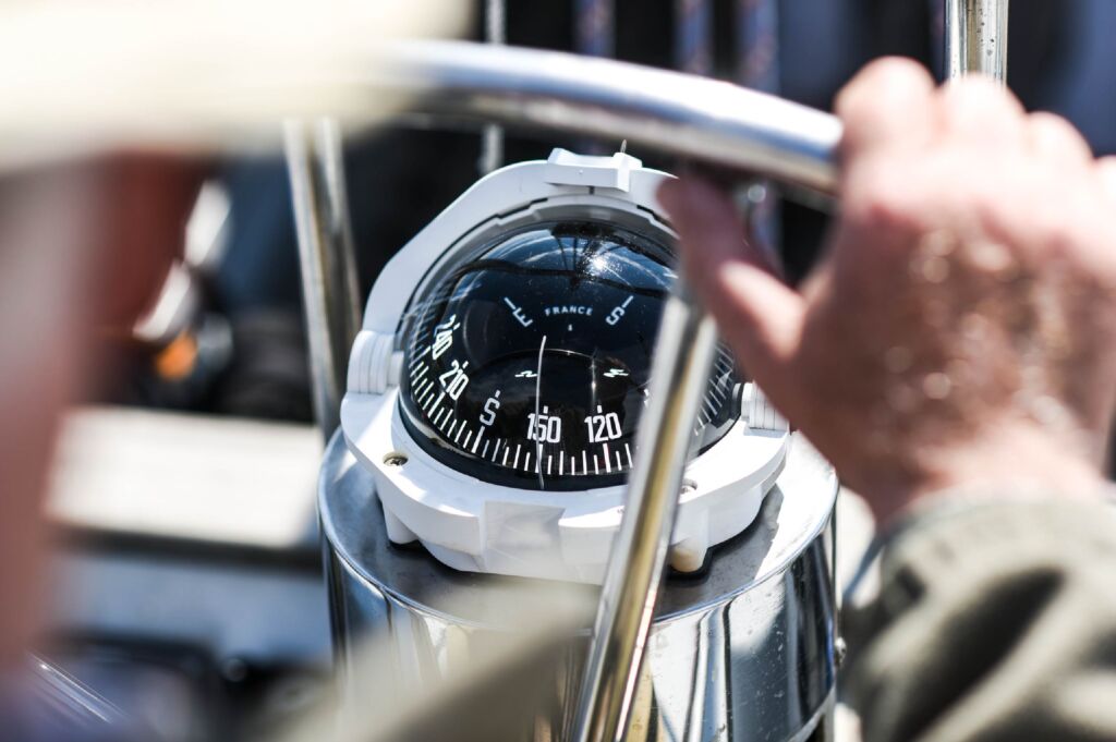 A nautical compass and steering wheel on a yacht-01