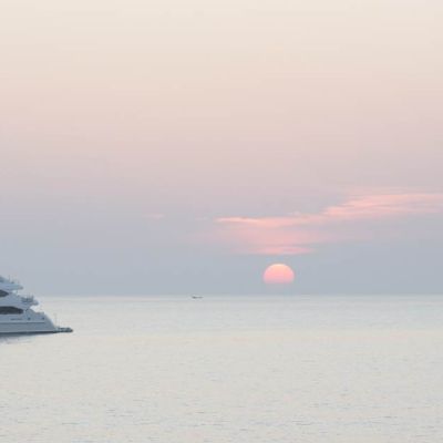 a superyacht sailing in front of the rising sun